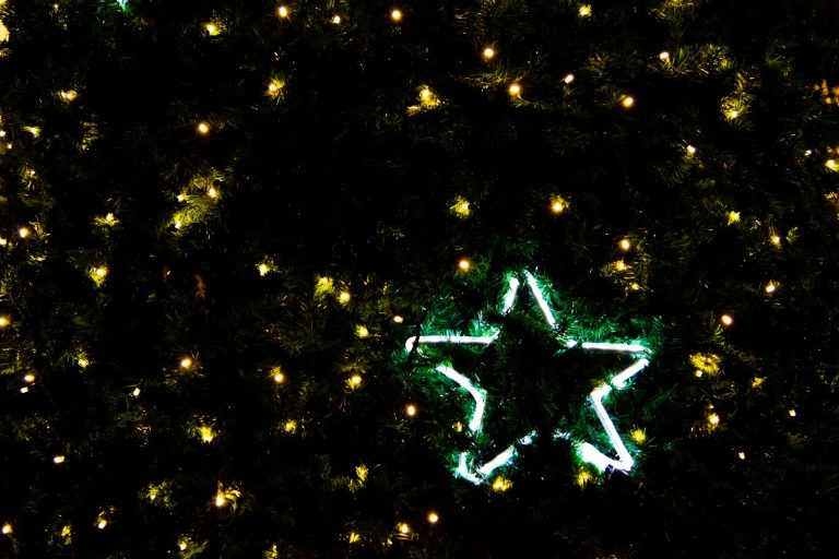 a lighted star on the side of a christmas tree