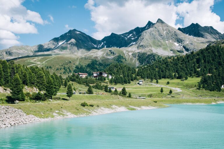 Scenic view of the Austrian Alps with a turquoise lake and lush greenery under a clear blue sky